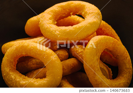 Golden crispy fried onion rings on black background Golden crispy fried onion rings on black background 140673683