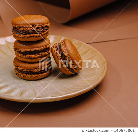 Chocolate macarons stacking on a plate against brown background 140673861