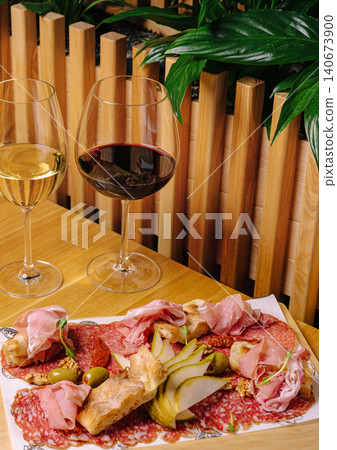 Antipasto platter with red and white wine glasses 140673900