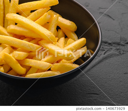 Golden french fries in bowl on dark background Golden french fries in bowl on dark background 140673929