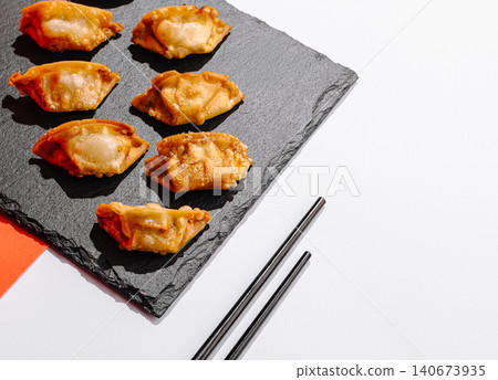 Fried gyoza dumplings on slate board with chopsticks Fried gyoza dumplings on slate board with chopsticks 140673935