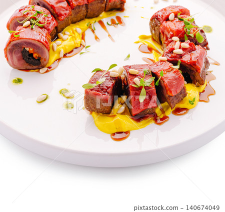 Gourmet meat appetizer with yellow puree and pine nuts 140674049