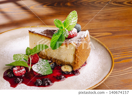 Cheesecake slices with berries, sauce, and mint Cheesecake slices with berries, sauce, and mint 140674157