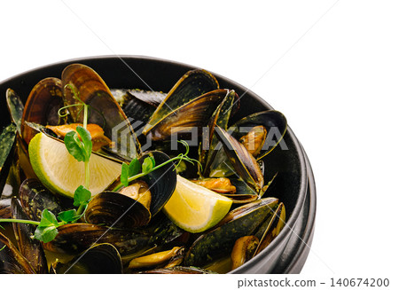 Steaming mussels in black bowl garnished with lime Steaming mussels in black bowl garnished with lime 140674200