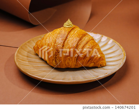 Croissant with pistachio cream on ceramic plate Croissant with pistachio cream on ceramic plate 140674201