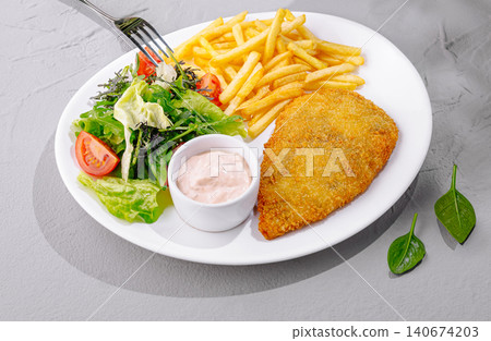 Crispy golden schnitzel with french fries, salad, and sauce Crispy golden schnitzel with french fries, salad, and sauce 140674203