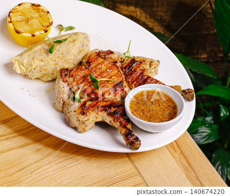 Grilled spatchcock chicken with mashed potatoes, lemon, and sauce Grilled spatchcock chicken with mashed potatoes, lemon, and sauce 140674220