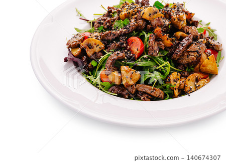 Beef salad with mushrooms, tomatoes, and sesame seeds 140674307