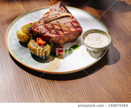 Grilled t-bone steak with roasted potatoes and sauce 140674369