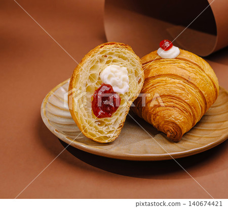 Croissant halves garnished with cream and strawberry jam 140674421