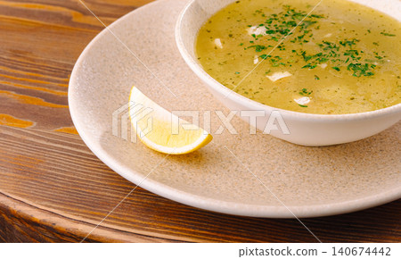 Chicken soup served with lemon wedge on rustic wooden table Chicken soup served with lemon wedge on rustic wooden table 140674442
