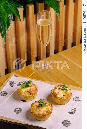 Savory mini quiche tartlets and sparkling wine glass on wooden table 140674447