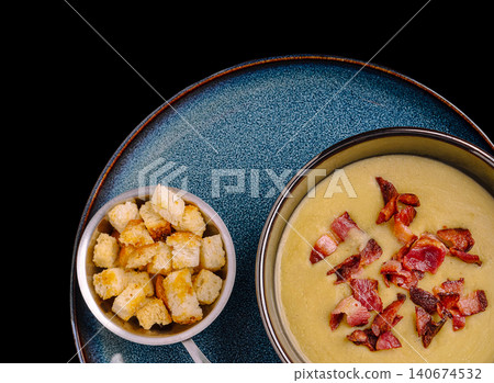 Cream soup serving with crispy bacon and croutons on blue plate Cream soup serving with crispy bacon and croutons on blue plate 140674532