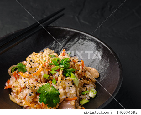 Fried rice with vegetables and chopsticks in black bowl Fried rice with vegetables and chopsticks in black bowl 140674592
