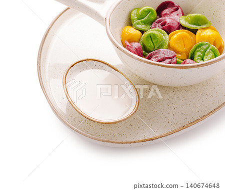 Colorful dumplings with sour cream dipping sauce on plate 140674648