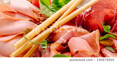 Italian charcuterie platter offering various cured meats and breadsticks Italian charcuterie platter offering various cured meats and breadsticks 140674660
