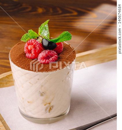 Tiramisu dessert served in glass with berries and mint Tiramisu dessert served in glass with berries and mint 140674684