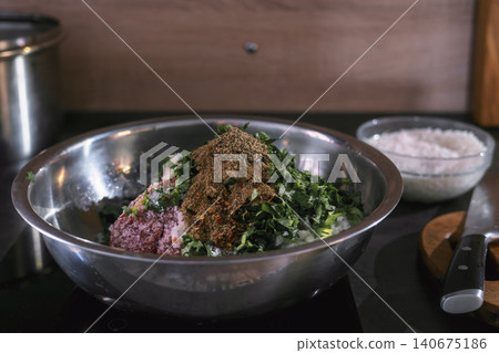 Close-up of a bowl of minced meat with herbs and spices on a kitchen table, tradition of making dolma at home, concept of delicious Middle Eastern and Mediterranean dishes Close-up of a bowl of minced meat with herbs and spices on a kitchen table, tradition of making dolma at home, concept of delicious Middle Eastern and Mediterranean dishes 140675186