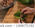 Top view of minced meat being wrapped in grape leaves during dolma preparation, a traditional Armenian dish concept 140675192