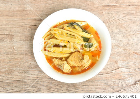 spicy boiled slice fresh bamboo shoot with pork in coconut milk Thai red curry soup on bowl spicy boiled slice fresh bamboo shoot with pork in coconut milk Thai red curry soup on bowl 140675401