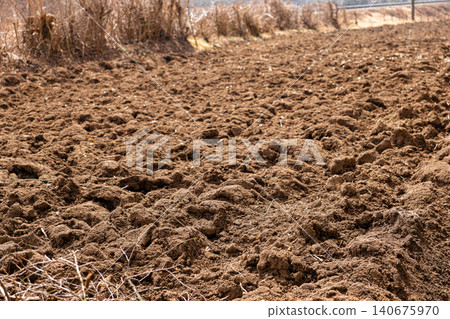 Freshly plowed brown soil in a rural field under bright sunlight, prepared for spring agricultural planting to ensure healthy crop growth and a productive season for local farming Freshly plowed brown soil in a rural field under bright sunlight, prepared for spring agricultural planting to ensure healthy crop growth and a productive season for local farming 140675970