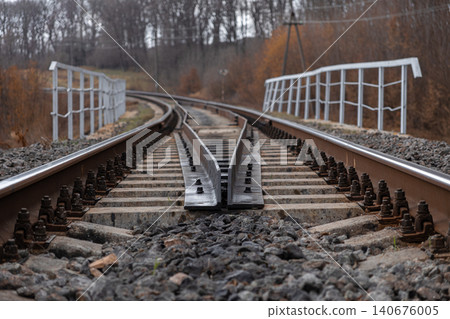 Industrial railroad tracks branching into two directions on a steel bridge represent travel options, future opportunities, decision making, and transitions in a rural landscape Industrial railroad tracks branching into two directions on a steel bridge represent travel options, future opportunities, decision making, and transitions in a rural landscape 140676005