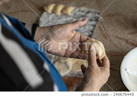 A senior person carefully shaping homemade dumplings by hand in a rustic kitchen, conveying culinary tradition, family heritage, and the heartwarming joy of preparing food from scratch A senior person carefully shaping homemade dumplings by hand in a rustic kitchen, conveying culinary tradition, family heritage, and the heartwarming joy of preparing food from scratch 140676449