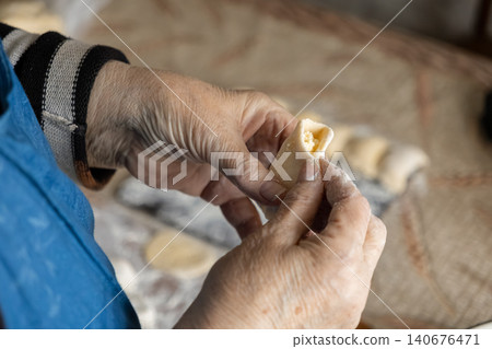 A senior person carefully shaping homemade dumplings by hand in a rustic kitchen, showcasing traditional culinary skills, nostalgic comfort, and the heritage of authentic cooking A senior person carefully shaping homemade dumplings by hand in a rustic kitchen, showcasing traditional culinary skills, nostalgic comfort, and the heritage of authentic cooking 140676471