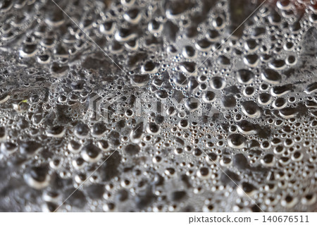 Condensed water droplets forming on a plastic film surface over hot steaming dumplings, capturing the warm moisture and texture of fresh food preparation in a commercial kitchen setup Condensed water droplets forming on a plastic film surface over hot steaming dumplings, capturing the warm moisture and texture of fresh food preparation in a commercial kitchen setup 140676511