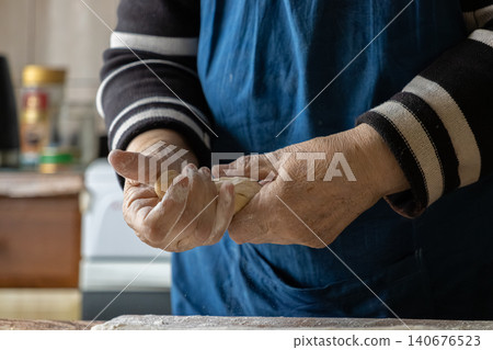 A senior person carefully shaping dough for traditional handmade dumplings in a home kitchen, highlighting culinary skill, authentic cooking techniques, and rustic food preparation art A senior person carefully shaping dough for traditional handmade dumplings in a home kitchen, highlighting culinary skill, authentic cooking techniques, and rustic food preparation art 140676523