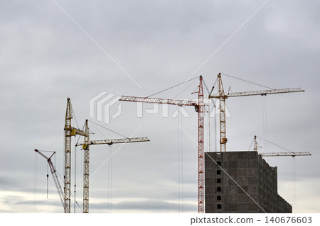 Giant tower crane over vacant building framework outdoors. Quiet city construction area featuring crane above vacant apartment framework 140676603