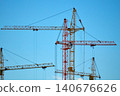 Construction crane working high above a city skyline during a clear day 140676626