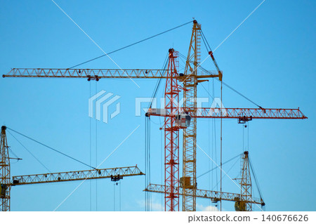 Construction crane working high above a city skyline during a clear day Construction crane working high above a city skyline during a clear day 140676626