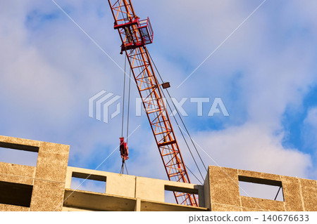Orange tower crane jib with trolley and pulleys in action Orange tower crane jib with trolley and pulleys in action 140676633