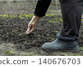 A senior person planting vegetable seeds in dark garden soil, using gentle hand gestures to ensure growth, representing a spring agricultural ritual for sustainable local food crops 140676703