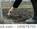 A senior hand planting seeds into rich dark soil in a spring vegetable garden, illustrating the dedication to sustainable food production and the connection to nature and earth 140676705