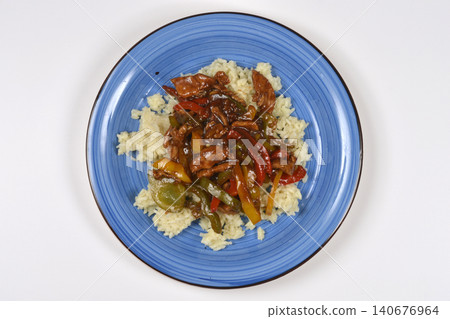 Stir fried pork with colorful bell peppers on white rice served on blue plate Stir fried pork with colorful bell peppers on white rice served on blue plate 140676964
