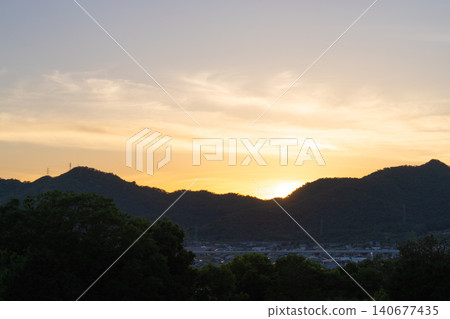 The sunset over the mountain range and the evening view of the town The sunset over the mountain range and the evening view of the town 140677435