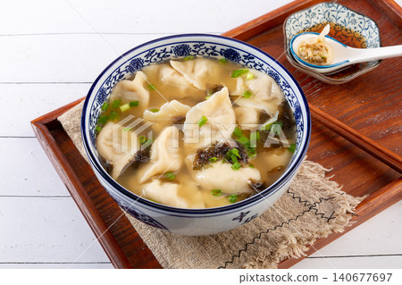 Chinese sour soup dumplings Jiaozi served in savory broth, with scallions and seaweed Chinese sour soup dumplings Jiaozi served in savory broth, with scallions and seaweed 140677697