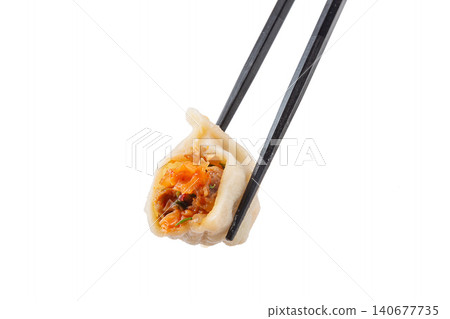 Close-up of chopsticks holding a spicy kimchi pork dumpling Mandu isolated on white background Close-up of chopsticks holding a spicy kimchi pork dumpling Mandu isolated on white background 140677735