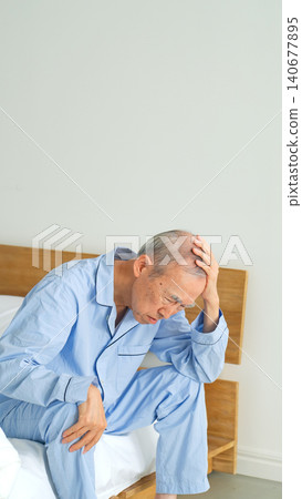 A senior man sitting on his bed, troubled. A senior man sitting on his bed, troubled. 140677895