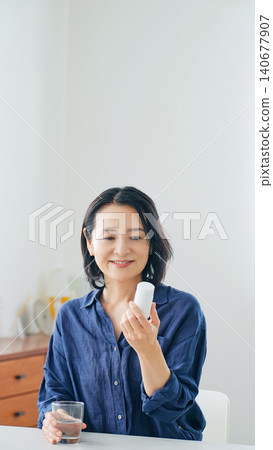 A middle-aged woman smiling as she holds a bottle of medicine. A middle-aged woman smiling as she holds a bottle of medicine. 140677907