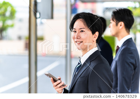 一名身穿西裝的男子在公車站等車。 140678329