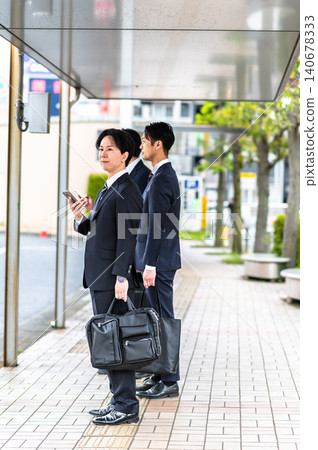 一名身穿西裝的男子在公車站等車。 一名身穿西裝的男子在公車站等車。 140678333