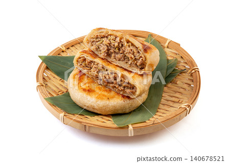 Golden crispy meat pies arranged on a green leaf inside a round bamboo steamer basket. Golden crispy meat pies arranged on a green leaf inside a round bamboo steamer basket. 140678521