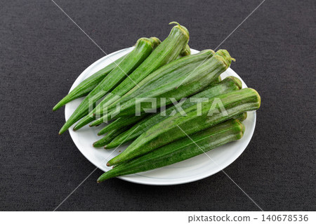 Fresh green okra pods on a white plate. Fresh green okra pods on a white plate. 140678536