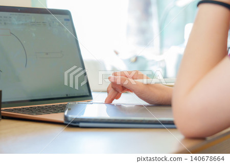 Focused student engaging in online learning with digital tablet and laptop at home for enhanced study experience Focused student engaging in online learning with digital tablet and laptop at home for enhanced study experience 140678664