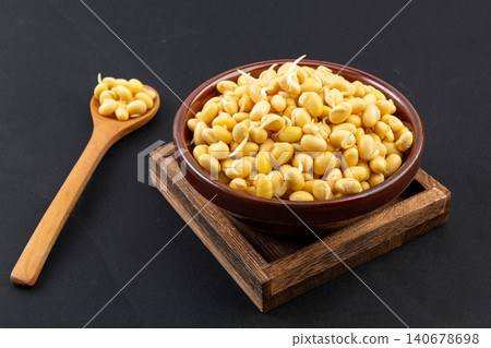 Top view of germinated yellow soybeans with tiny sprouts in a black bowl 140678698