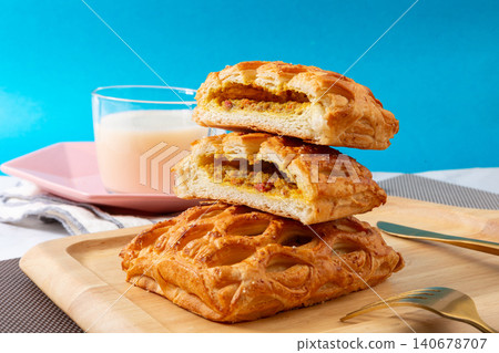 High angle view of golden curry chicken lattice pies served on a wooden cutting board with a glass of milk and cutlery. High angle view of golden curry chicken lattice pies served on a wooden cutting board with a glass of milk and cutlery. 140678707