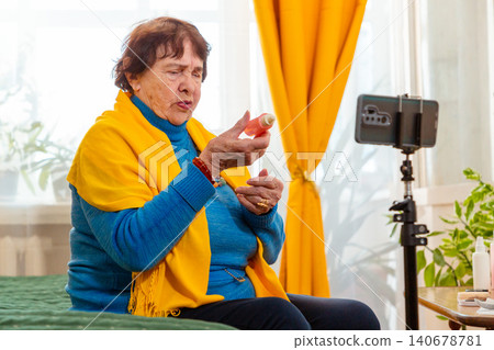 Caucasian grandmother sharing makeup advice and personal care experiences through social media content. Influencer lifestyle concept. Technology and retirement. Mid shot Caucasian grandmother sharing makeup advice and personal care experiences through social media content. Influencer lifestyle concept. Technology and retirement. Mid shot 140678781